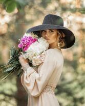 Девушка в черной шляпе с букетом пионов